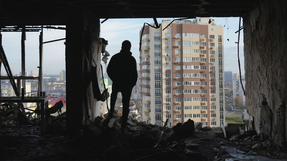 Man stands in rubble looking out at an apartment building