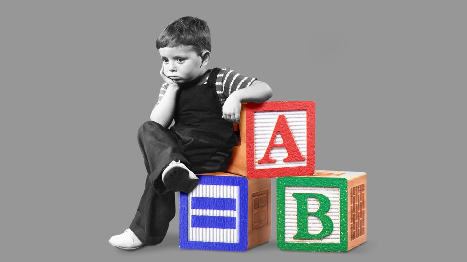 A kid pondering on a pile of ABC blocks.