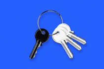 A photo illustration of four keys on a keychain, three white facing to the right and one black facing to the left, all on a blue background.