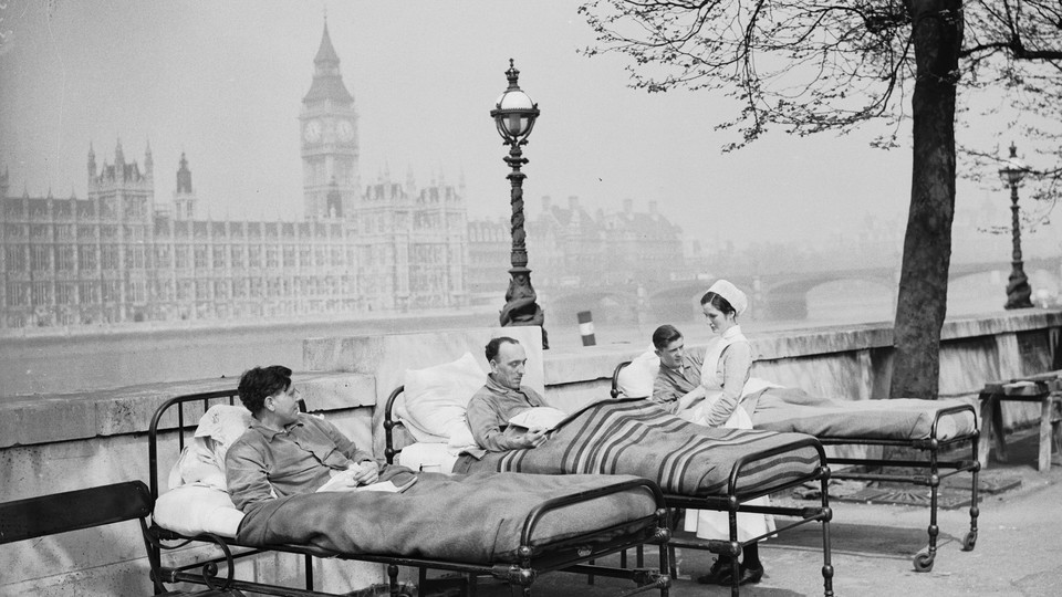 Three men sit in outdoor hospital beds with Westminster Palace in the background.