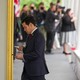 Marco Rubio tapping at his phone while walking past Donald Trump's portrait