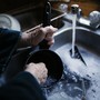 An elderly woman's hands washing a pot in a sink