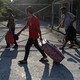 A photograph of migrants walking with suitcases