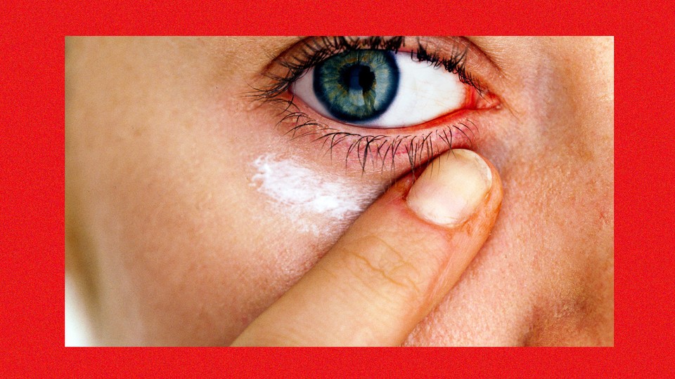A close-up of a person applying cream beneath their eye