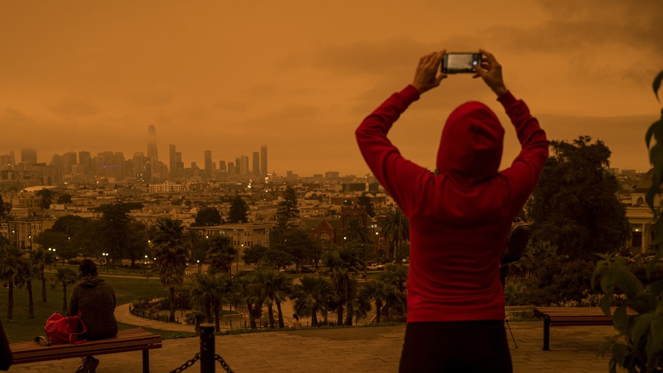 A woman taking a photo of an orange sky