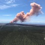 A plume of red-gray ash rises out of a Hawaiian volcano.