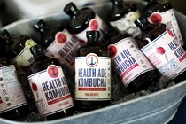 A bucket of glass bottles of kombucha over ice