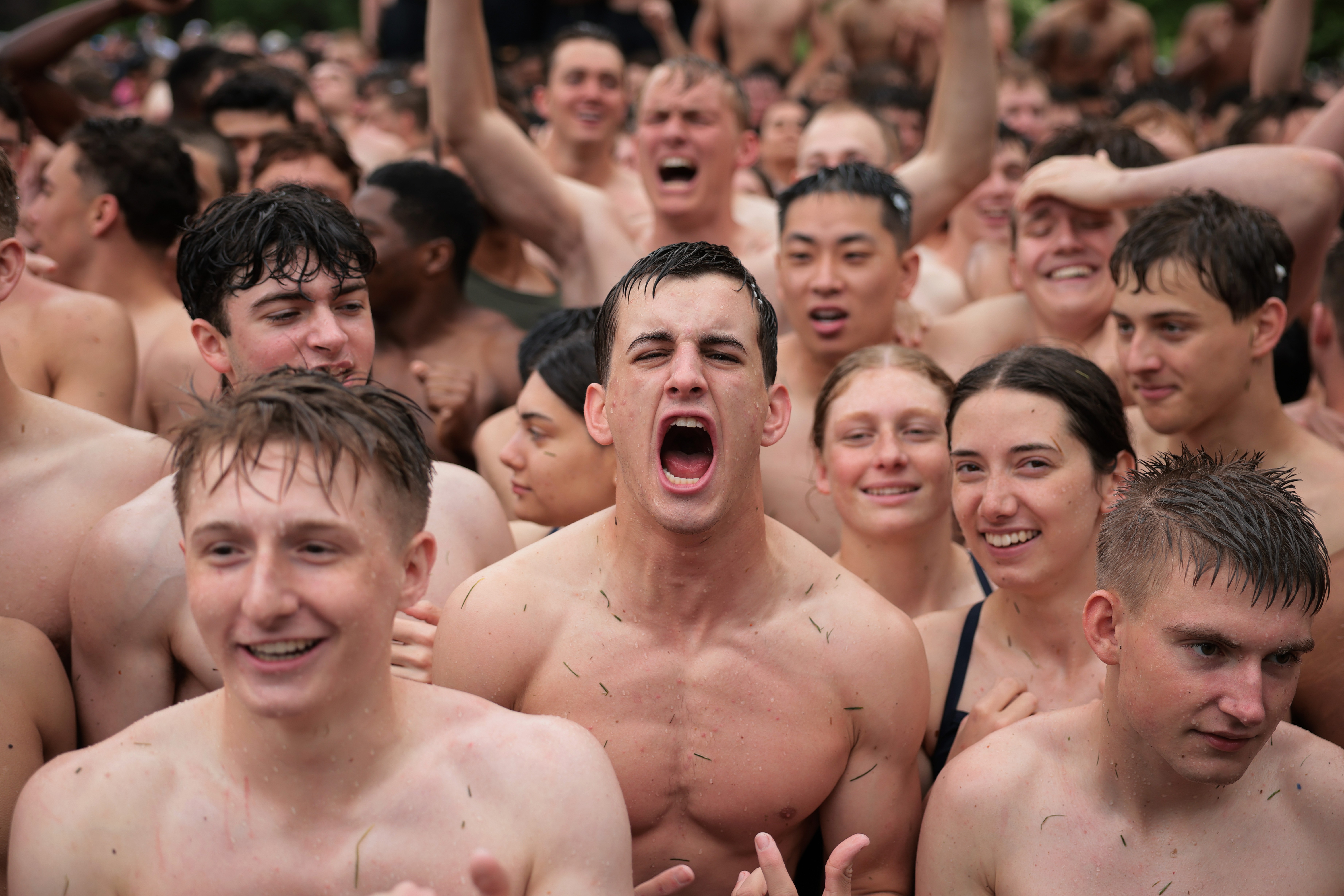 A crowd of young men and women shout while celebrating their completion of a challenge.