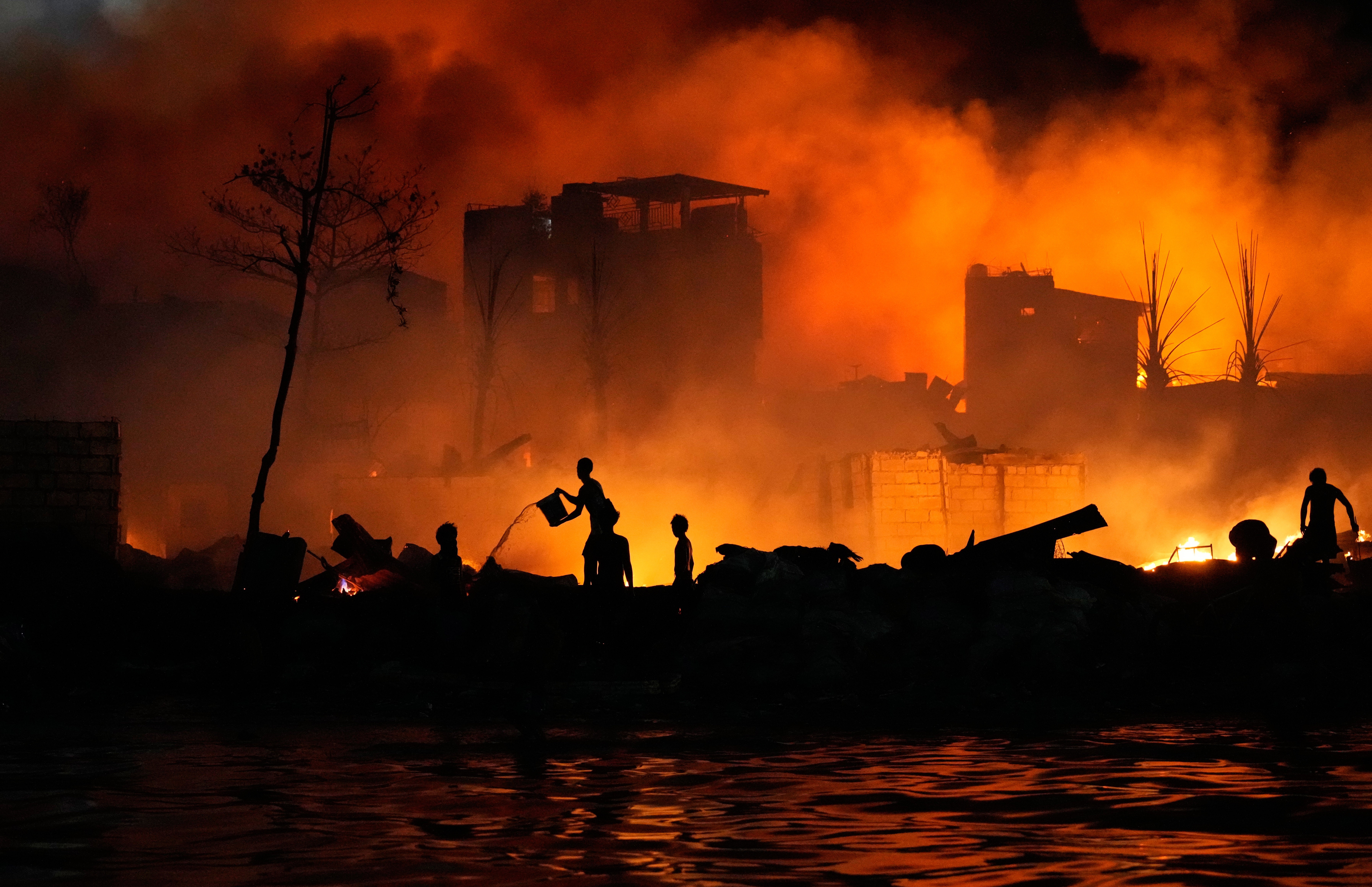 Residents use buckets of water to try to control a fire in a poor neighborhood.