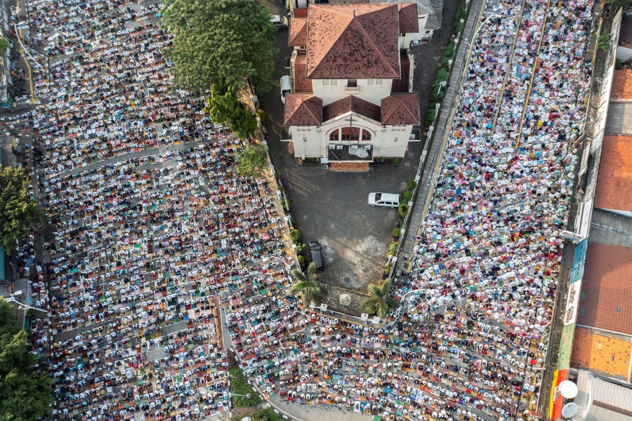An aerial view of a large crowd of people praying in a street