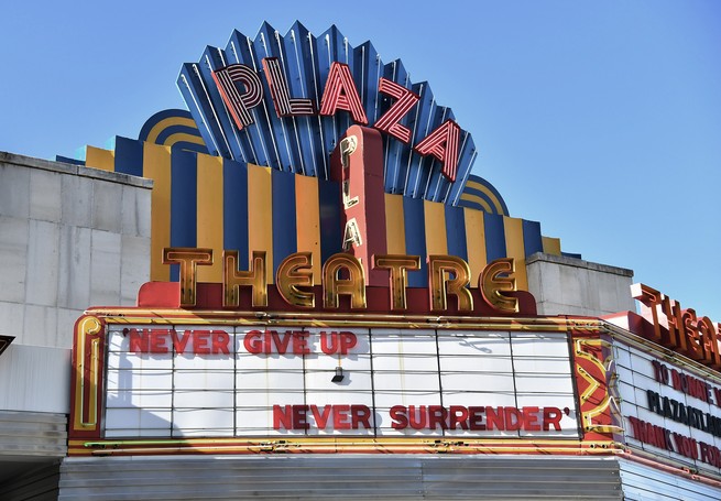 A view of the Plaza Theatre with a marquee that reads "Never Give Up, Never Surrender."