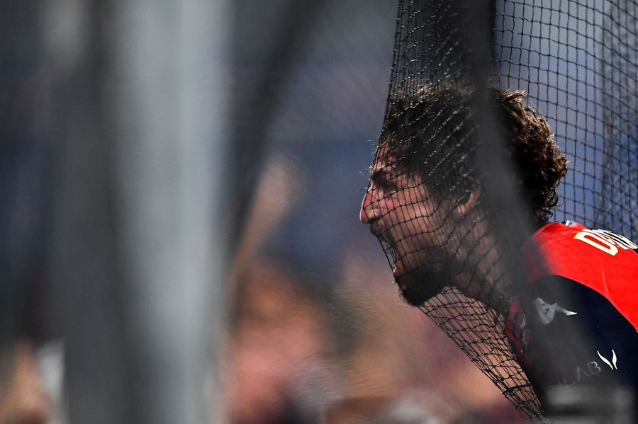 A soccer player celebrates with his face in the net of the goal.