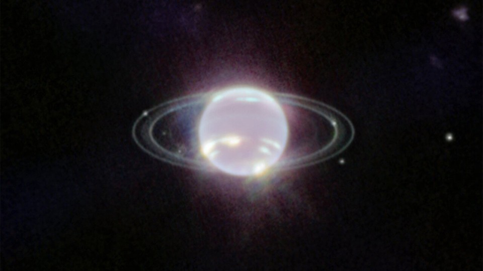 Neptune resembles a shimmery, white orb, and its rings are visible, in a new image from the James Webb Space Telescope.