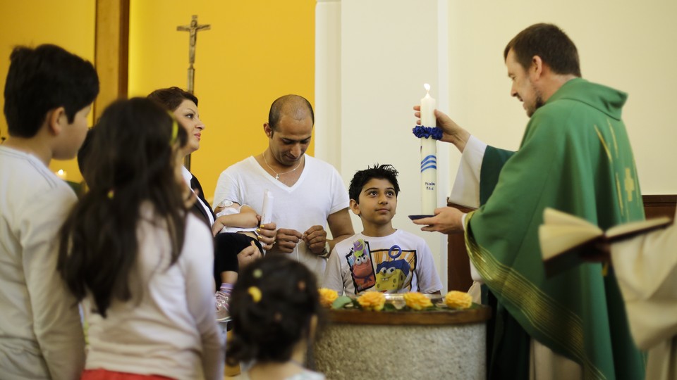 Pastor Gottfried Martens lights a candle during a service to baptize people from Iran, in the Trinity Church in Berlin, Aug. 30, 2015.