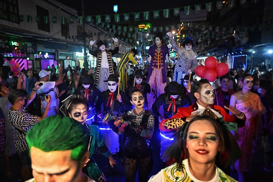 Revelers in costume take part in a Halloween parade at night.