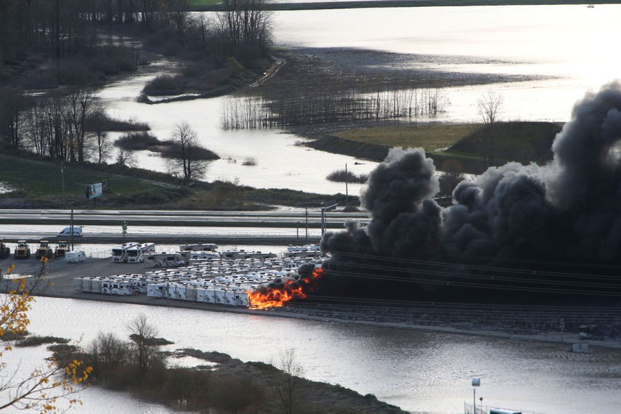 RV trailers are seen burning in a lot surrounded by floodwater.