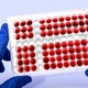 A tray of test tubes filled with a red liquid, in a pattern that forms the Danish national flag