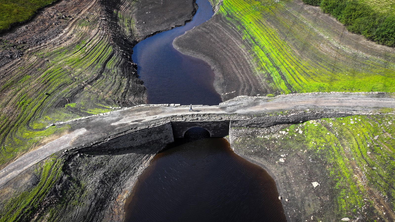 An aerial view of an ancient bridge over a drying reservoir.