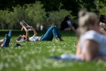 A person laying in the grass and reading