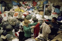 People sorting through enormous piles of recycled clothing.