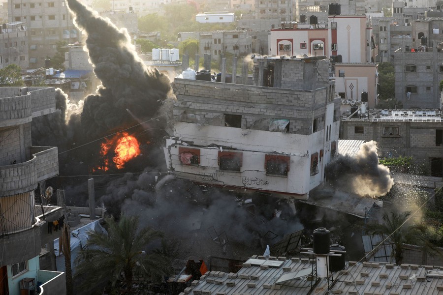 An explosion erupts from the lower section of a three-story building, as it begins to collapse.