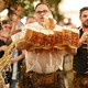 A man carrying more than 30 full beer mugs spills one or two.