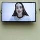 A TV screen showing the face of Oleksandra Matviychuk, as if on a video-call
