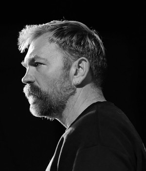 black-and-white photo of man with beard turned to side