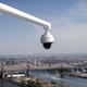 A security camera hangs from the roof of the Secretariat Building at the United Nations headquarters with the East River and Queensboro Bridge in the background in New York City.