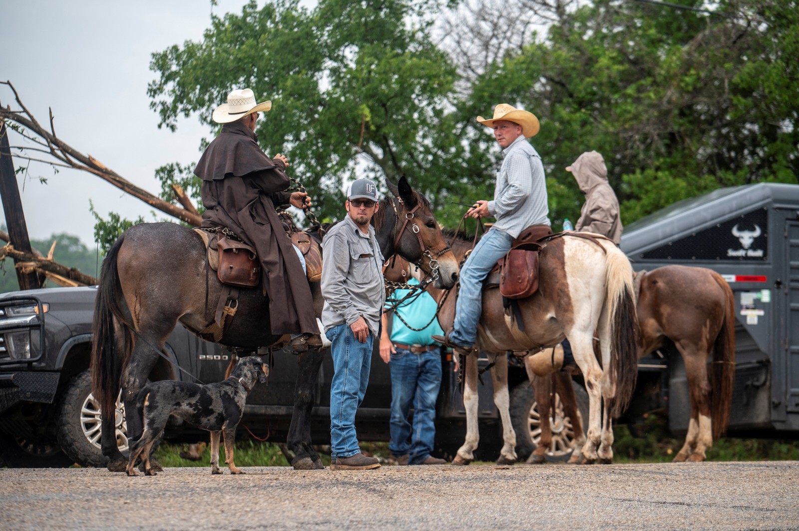 Several people on horseback gather and talk, before heading out to search for flood victims.
