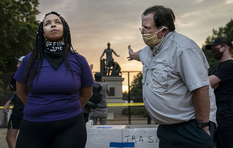 A man and woman argue in front of a statue of Abraham Lincoln and a kneeling slave.