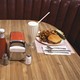 A table at a diner with a hamburger, french fries, milkshakes, and ketchup