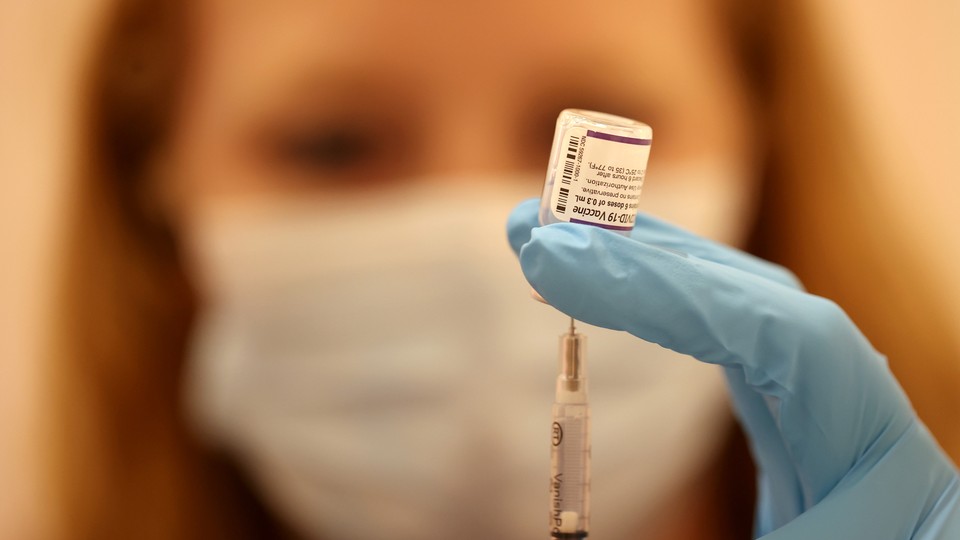 A pharmacist fills a syringe with the Pfizer COVID-19 booster vaccine.