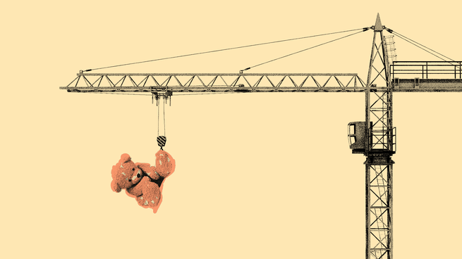 A crane lifts up a teddy bear by its foot.