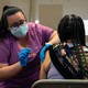 a health worker administers a vaccine to a person sitting in a chair