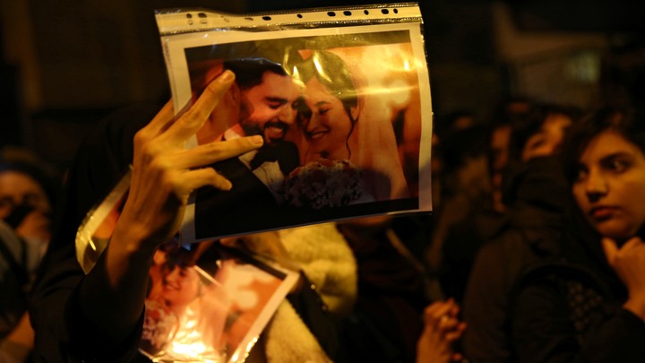 a woman holds a wedding picture depicting two victims of the crash of Ukraine International Airlines Flight 752.