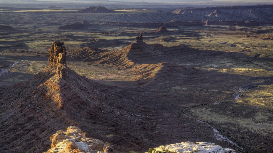 Cedar Mesa Valley of the Gods in Utah. Rock formations rise out of red soil.