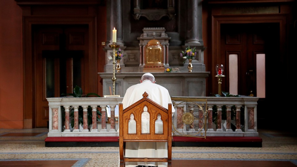 At a church in Ireland, Pope Francis sits and prays in front of a candle lit to remember victims of abuse.