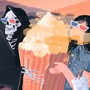 A moviegoer shares popcorn with a grim reaper.