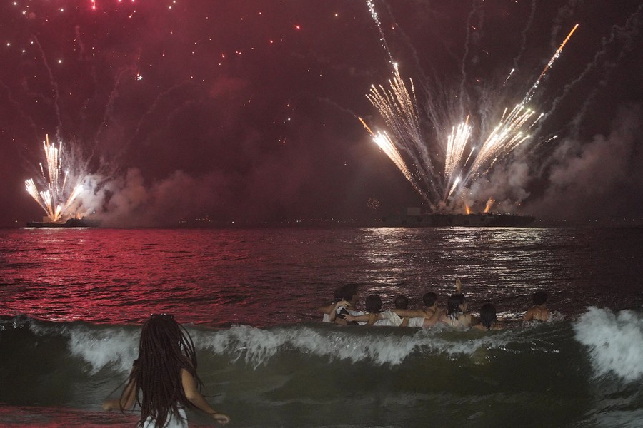 Revelers enjoy fireworks, seen from a beach.