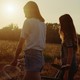Two friends walking with a bike in a field