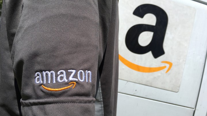 An Amazon driver stands next to an Amazon truck.