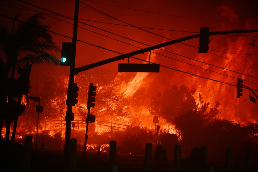 Fires burn along a hillside near a road intersection.