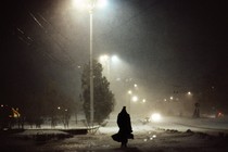 nighttime photo of the back of a man walking down the street