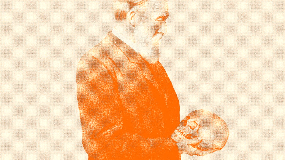 A man looks down, holding a skull