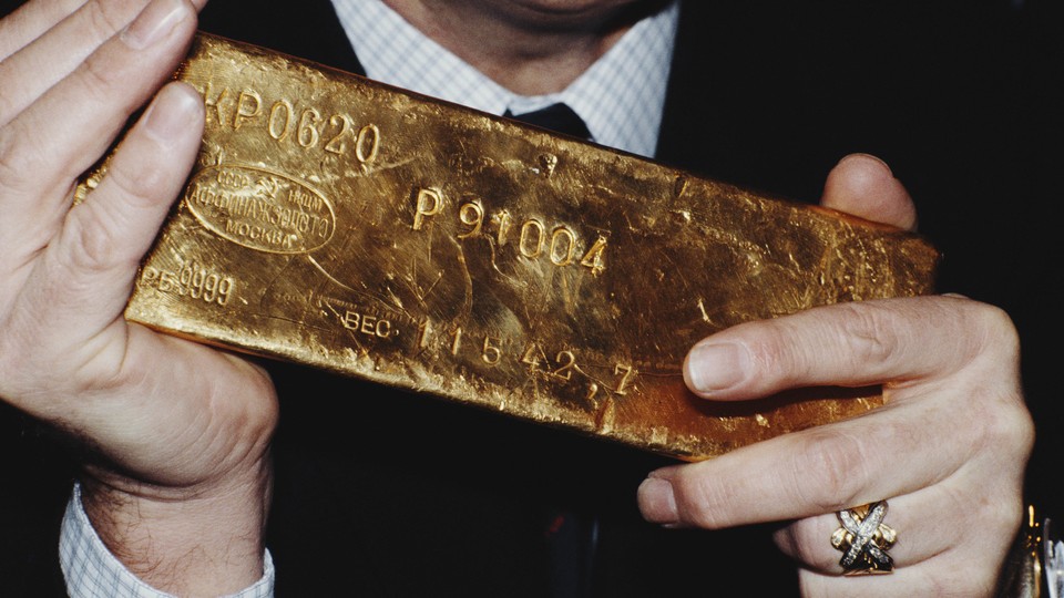 Color photograph of a person's hands holding a bar of gold.