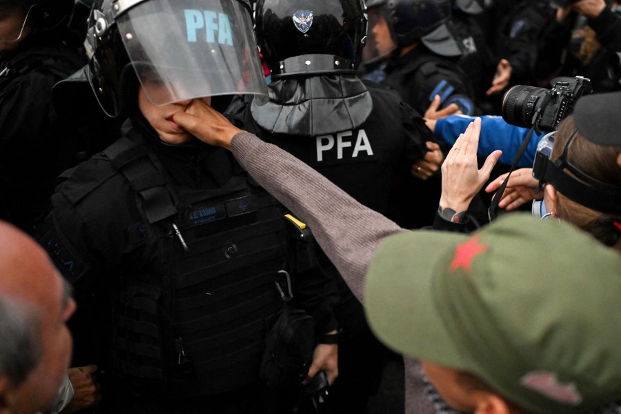 A demonstrator punches the face of a riot police officer during a protest.