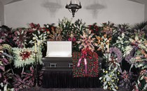 A casket at a funeral surrounded by flowers