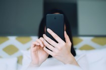 photograph of a woman using phone, held directly in front of her face