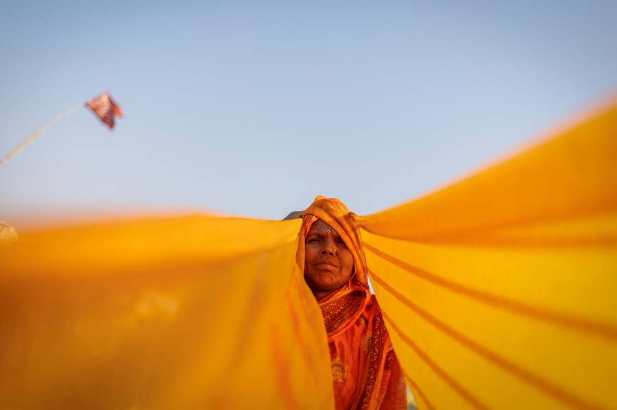 A view from below, looking up toward a woman with long colorful cloth hanging from her head